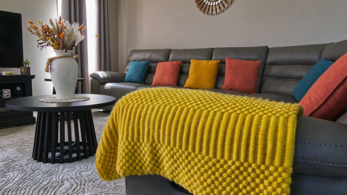 Canapé de salon avec un plaid lesté plié et une lumière douce
