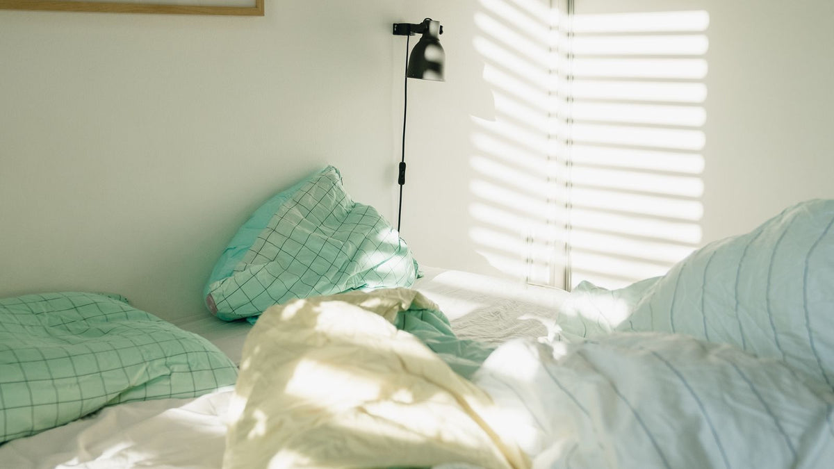 Lit défait avec une couverture lestée dans la lumière du matin