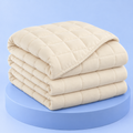 Couverture lestée Milo crème, pliée sur fond bleu Pondoa #creme